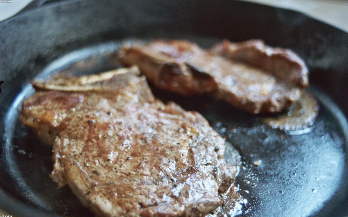 A well-seasoned cast iron skillet on a stovetop with a rustic kitchen behind it