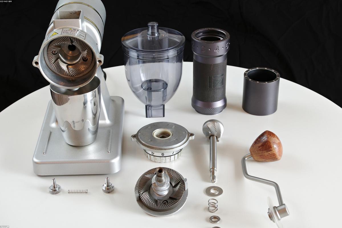 A burr coffee grinder on a kitchen counter beside a jar of whole coffee beans