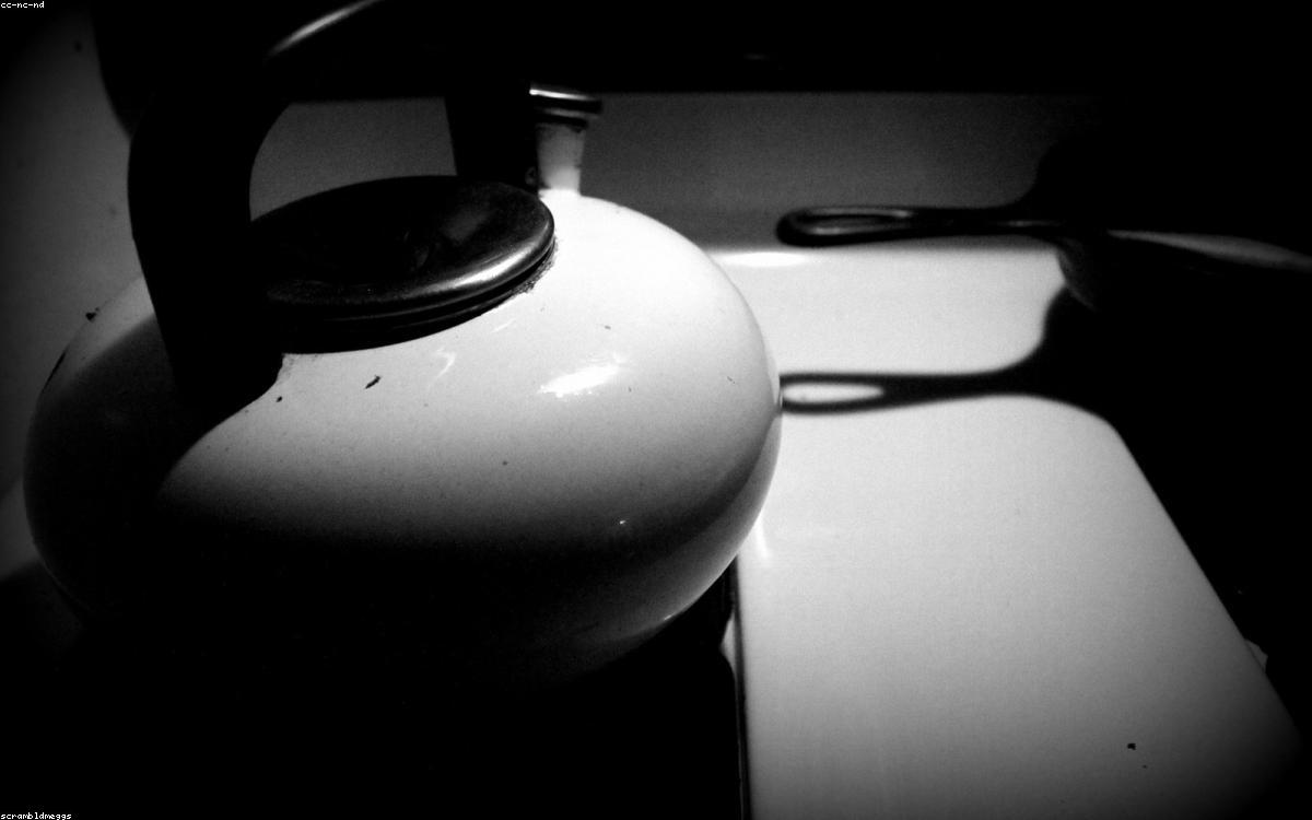 A stainless steel electric kettle pouring water into a teacup