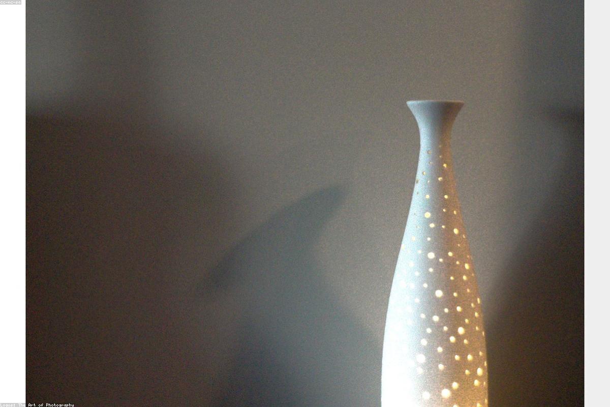 A ceramic essential oil diffuser releasing mist beside eucalyptus on a console table