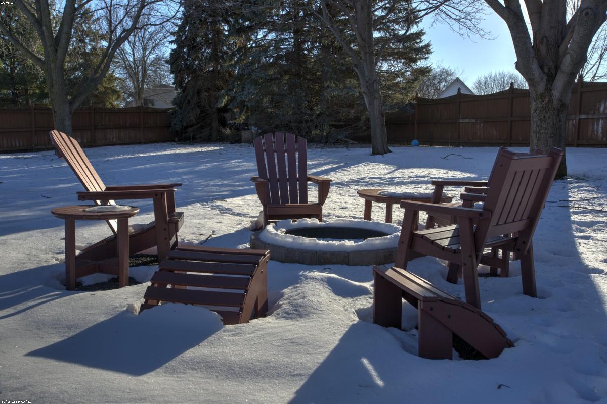 A smokeless fire pit with chairs gathered around it on a patio at evening