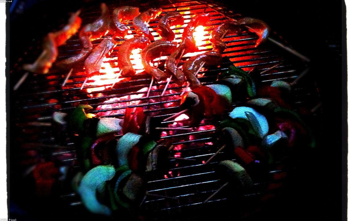 A gas grill with food cooking on a sunny backyard patio